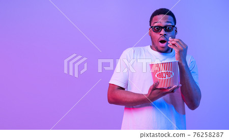 Young African Guy In 3D Glasses Eating Popcorn While Watching Scary Movie 76258287