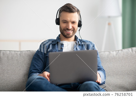 Relaxed man watching movie, using laptop and headphones Relaxed man watching movie, using laptop and headphones 76258701