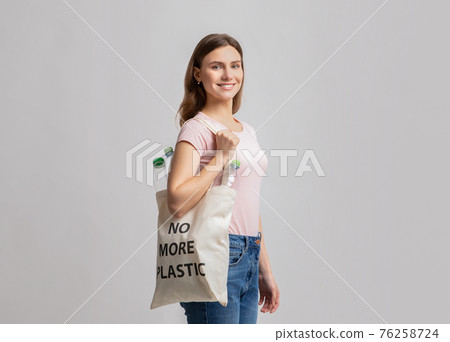 Smiling Young Woman Carrying Eco Tote Bag With No More Plastic Inscription 76258724