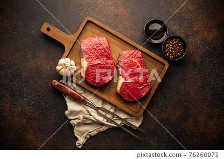 Two raw meat steaks on wooden board Two raw meat steaks on wooden board 76260071