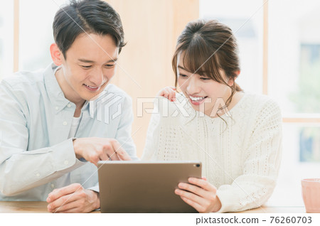 Young couple sitting at a table and looking at a tablet Young couple sitting at a table and looking at a tablet 76260703