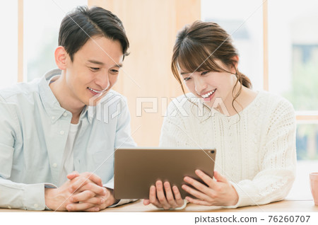Young couple sitting at a table and looking at a tablet Young couple sitting at a table and looking at a tablet 76260707
