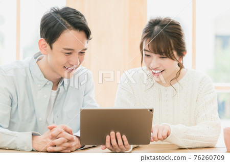 Young couple sitting at a table and looking at a tablet 76260709