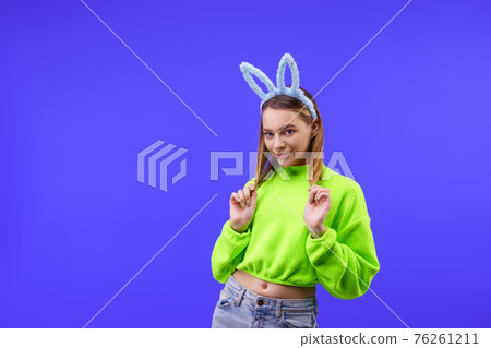 young woman in bunny ears on a blue background young woman in bunny ears on a blue background 76261211