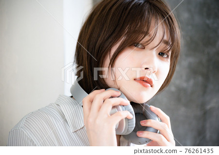 A woman who takes off her headphones and wears it around her neck 76261435