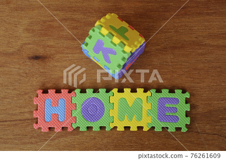 HOME word made from colourful soft rubber mat. Isolated on a wood texture board background.  76261609