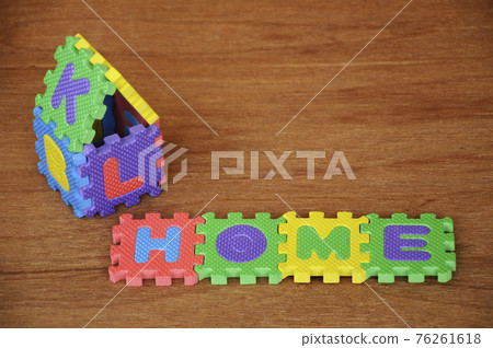 HOME word made from colourful soft rubber mat. Isolated on a wood texture board background.  76261618