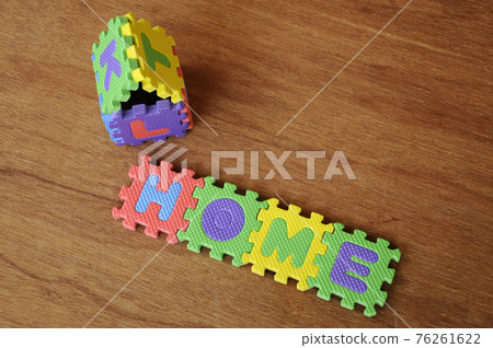 HOME word made from colourful soft rubber mat. Isolated on a wood texture board background.  76261622
