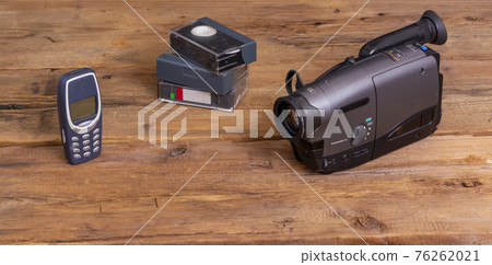 Old telephone,. vhs cassete and vhs video camera on wooden background Old telephone,. vhs cassete and vhs video camera on wooden background 76262021