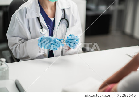 The nurse is preparing to inject the drug into the patient's vein, holding a syringe with the drug in her hands 76262549