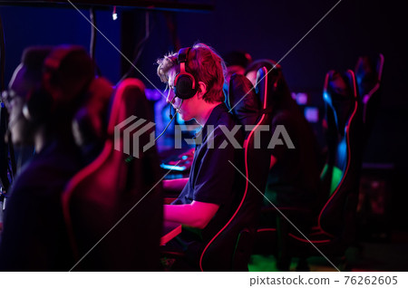Training bootcamp for professional esports players. Young cyber-athletes play an online shooter game. Glowing keyboard, neon light. Training bootcamp for professional esports players. Young cyber-athletes play an online shooter game. Glowing keyboard, neon light. 76262605