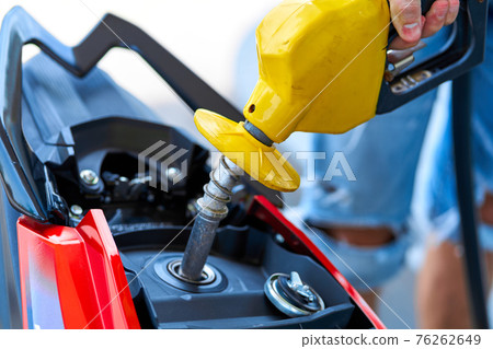 Refueling a motorbike. Close-up of a fuel nozzle inserted into a gas tank Refueling a motorbike. Close-up of a fuel nozzle inserted into a gas tank 76262649