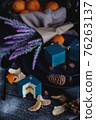 Blue cake filled with orange and tangerine in the shape of a cube. Nearby on a black table are ingredients oranges, tangerines, nuts. Rustic style 76263137