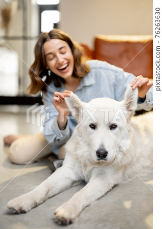 Happy woman with a dog at home 76263630
