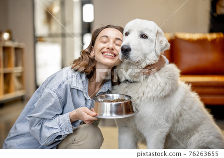 Woman feeding dog with a dry food at home Woman feeding dog with a dry food at home 76263655