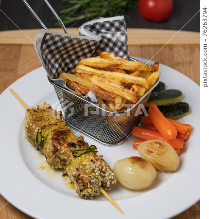 Lamb skewer with sesame seeds, served with fries, carrot, zucchini and white onions 76263794