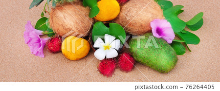 Tropical fruit on a sandy beach. Wide photo. 76264405