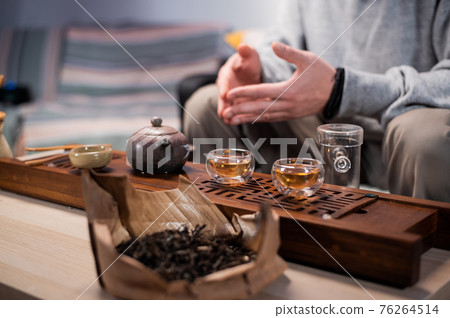 Close-up of the chinese tea ceremony ritual. Hands pour hot water into special vessels on a bamboo board. Close-up of the chinese tea ceremony ritual. Hands pour hot water into special vessels on a bamboo board. 76264514