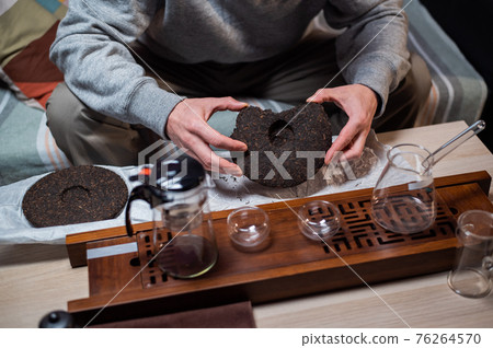 Shot without a face. Close-up of the master's hands picking a tea cake with a needle for a tea ceremony or chinese tea tasting. 76264570