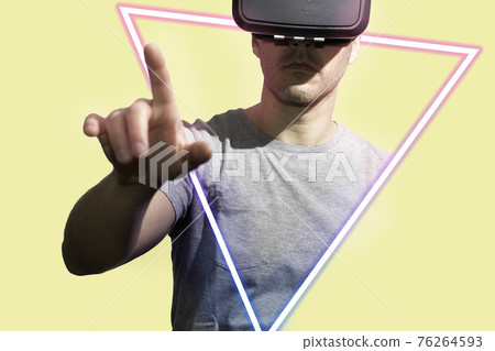 Man's playing and using VR-glasses in neon light isolated on yellow background. Male portrait. Concept of modern gadgets and technologies. 76264593