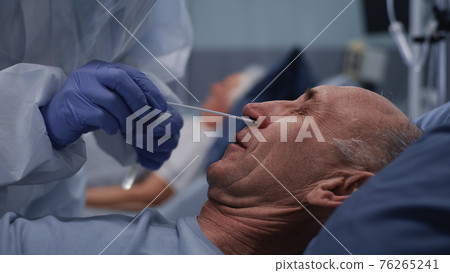 Crop doctor taking coronavirus test from senior patient 76265241