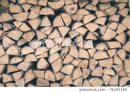 Firewood or fuelwood stacked by a wall. Texture woodpile 76265399