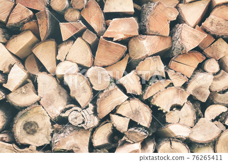 Firewood or fuelwood stacked by a wall. Texture woodpile 76265411