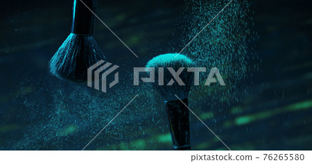 explosion of green and blue eyeshadows on dark background. makeup brushes explosion of green and blue eyeshadows on dark background. makeup brushes 76265580