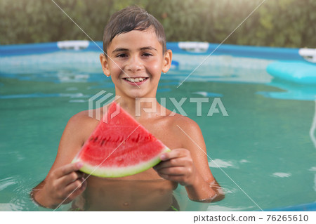 happy boy swims in the pool, holds a slice of watermelon, smiling, summer and travel concept happy boy swims in the pool, holds a slice of watermelon, smiling, summer and travel concept 76265610