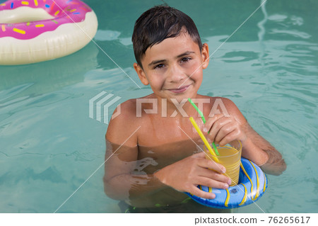 smiling boy drinking a refreshing drink while swimming in the pool or in the sea, vacation concept smiling boy drinking a refreshing drink while swimming in the pool or in the sea, vacation concept 76265617