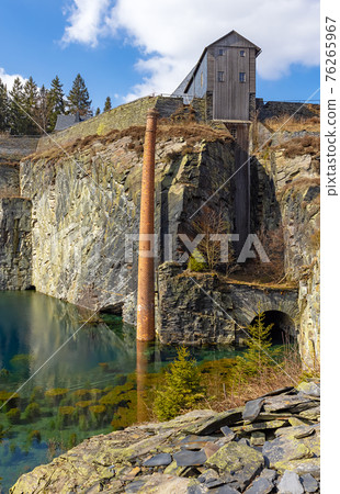 Lehesten, slate park in Thuringia, Germany. Abandoned oil shale plant. Artificial lake with brick chimney reflection. Lehesten, slate park in Thuringia, Germany. Abandoned oil shale plant. Artificial lake with brick chimney reflection. 76265967