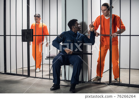 A male warden guards cells with dangerous criminals in a high-security prison. Dangerous profession. A male warden guards cells with dangerous criminals in a high-security prison. Dangerous profession. 76266264