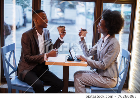 African partners drinking coffee during meeting at cafe African partners drinking coffee during meeting at cafe 76266865