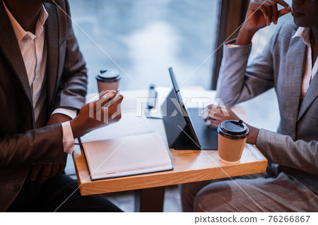 Close up of business partners working on tablet at cafe Close up of business partners working on tablet at cafe 76266867