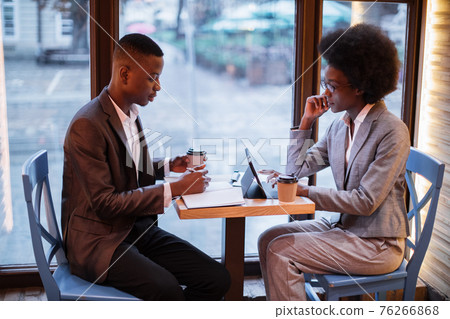 Two african people in formal clothes sitting at cafe Two african people in formal clothes sitting at cafe 76266868