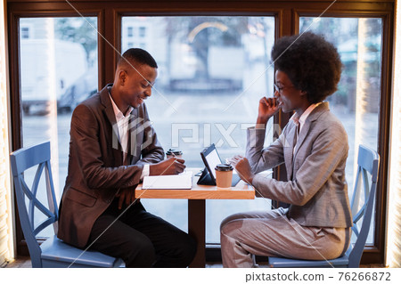 Business partners using gadgets for work at cafe Business partners using gadgets for work at cafe 76266872