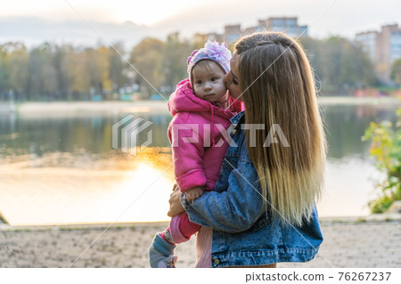 Young mother with her daughter on a warm autumn evening. 76267237