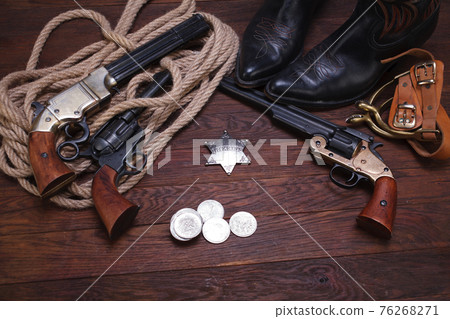 Old western revolver guns with sheriff badge and silver dollars with hat, rope and cowboy boots Old western revolver guns with sheriff badge and silver dollars with hat, rope and cowboy boots 76268271