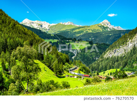 Train with trailers crossing the Alps in Austria 76270570