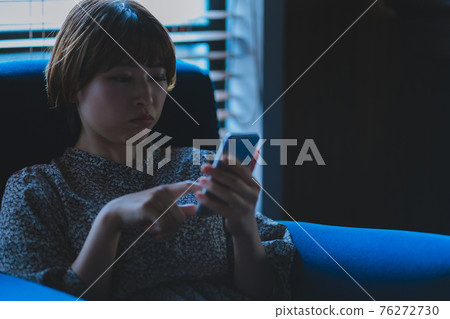A smartphone and a woman in her twenties A smartphone and a woman in her twenties 76272730