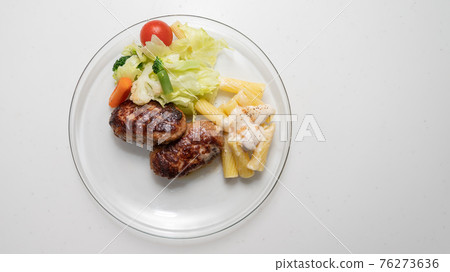 Place hamburger and vegetables on a transparent plate Place hamburger and vegetables on a transparent plate 76273636