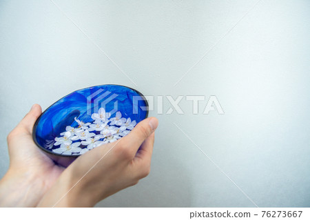 一個藍色的碗,裡面裝滿了櫻花和水 一個藍色的碗,裡面裝滿了櫻花和水 76273667