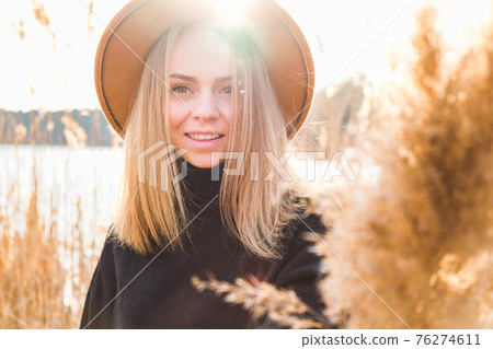European blonde woman with beige hat in black sweater in the countryside. Golden hour, cottagecore. Local travel. Slow living. Mental health. Pampas grass European blonde woman with beige hat in black sweater in the countryside. Golden hour, cottagecore. Local travel. Slow living. Mental health. Pampas grass 76274611