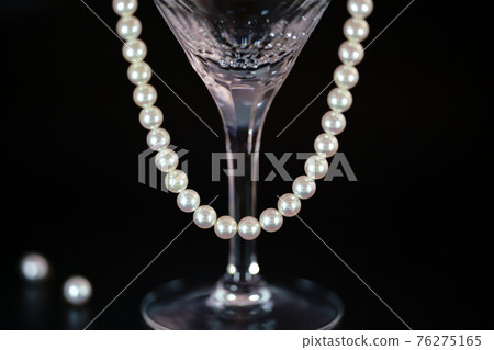 Pearl necklace and glass black background Pearl necklace and glass black background 76275165