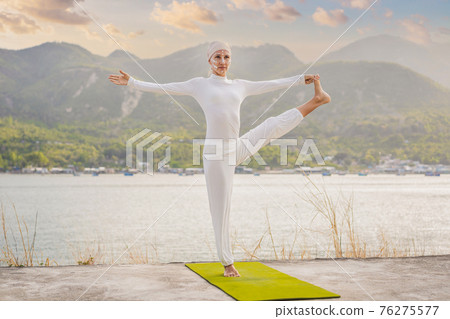 Kundalini yoga woman in white clothes and turban practices yoga kundalini on the background of the sea, mountains and sunset. Fighting face painting of the Indians shows her inner world. Visual Kundalini yoga woman in white clothes and turban practices yoga kundalini on the background of the sea, mountains and sunset. Fighting face painting of the Indians shows her inner world. Visual 76275577
