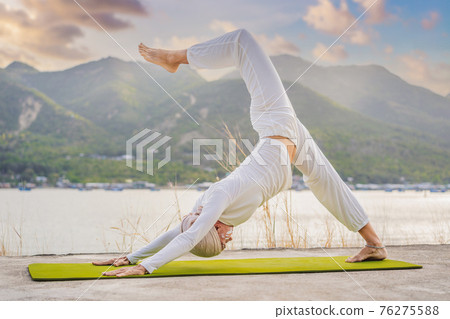 Kundalini yoga woman in white clothes and turban practices yoga kundalini on the background of the sea, mountains and sunset. Fighting face painting of the Indians shows her inner world. Visual Kundalini yoga woman in white clothes and turban practices yoga kundalini on the background of the sea, mountains and sunset. Fighting face painting of the Indians shows her inner world. Visual 76275588
