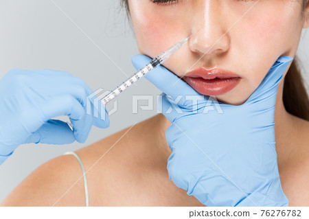 A syringe is placed on a woman's nose 76276782
