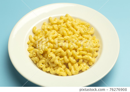 Pasta background. Mac and Cheese pasta on a blue background. American style Italian pasta with cheese. Pasta background. Mac and Cheese pasta on a blue background. American style Italian pasta with cheese. 76276908