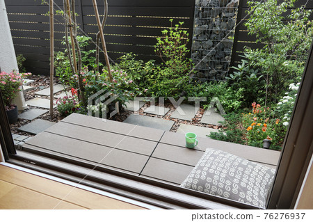 Coffee break on the wooden deck (veranda) in a small garden with a gabion 76276937
