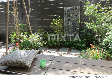 Coffee break on the wooden deck (veranda) in a small garden with a gabion Coffee break on the wooden deck (veranda) in a small garden with a gabion 76276940
